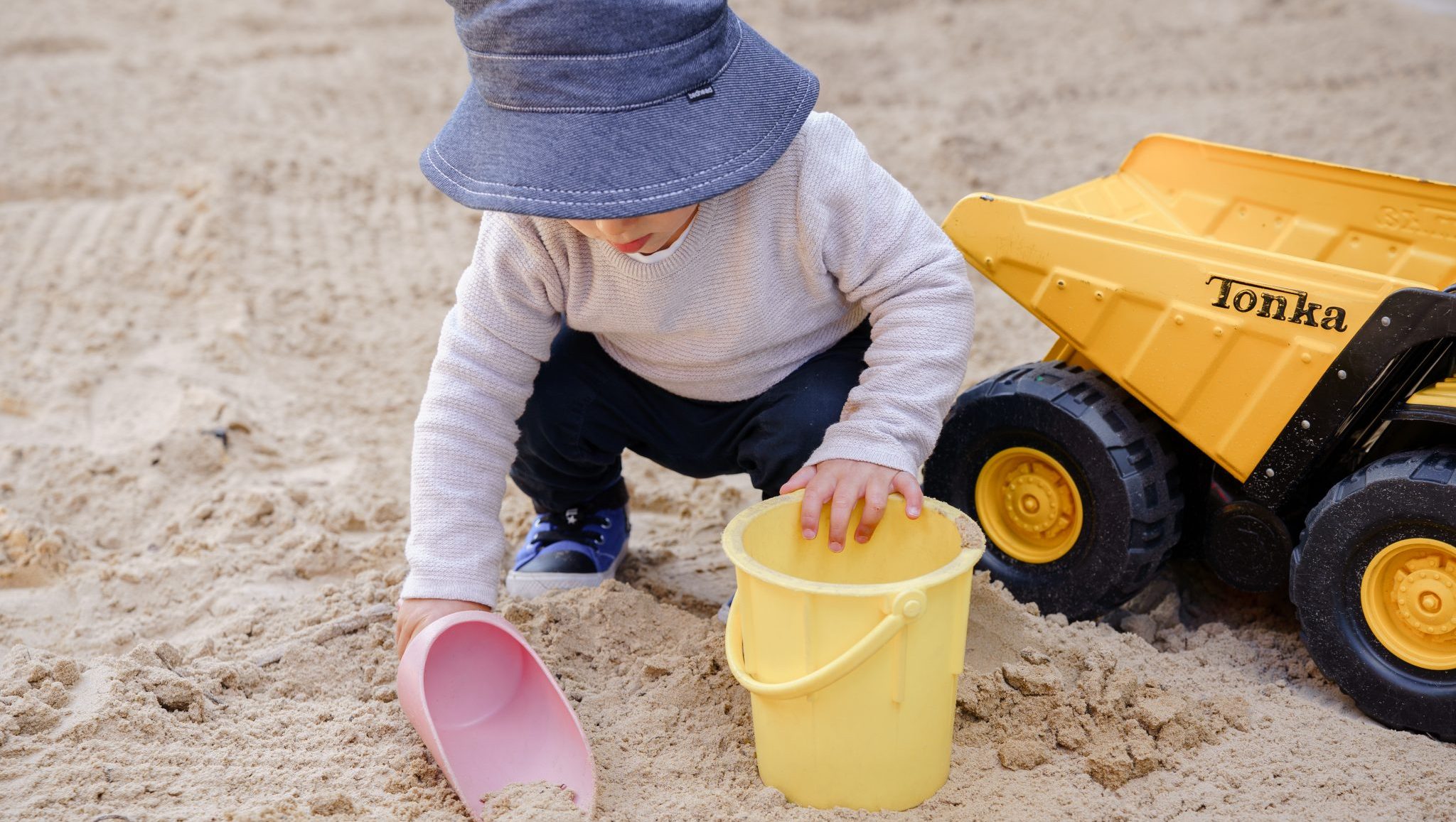 Explore & Develop, child playing in sandpit with bucket and truck
